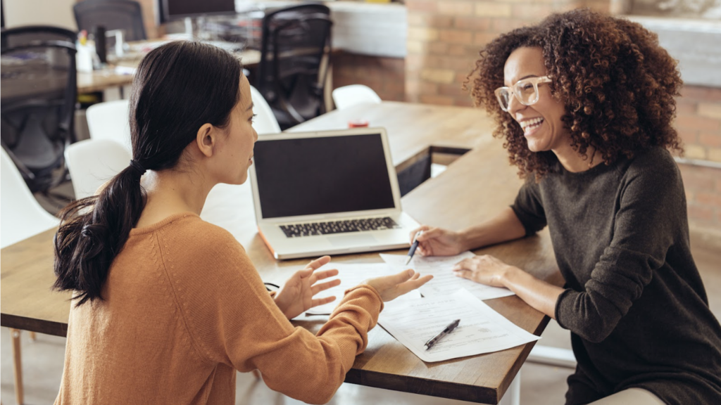 Two women at a desk talking